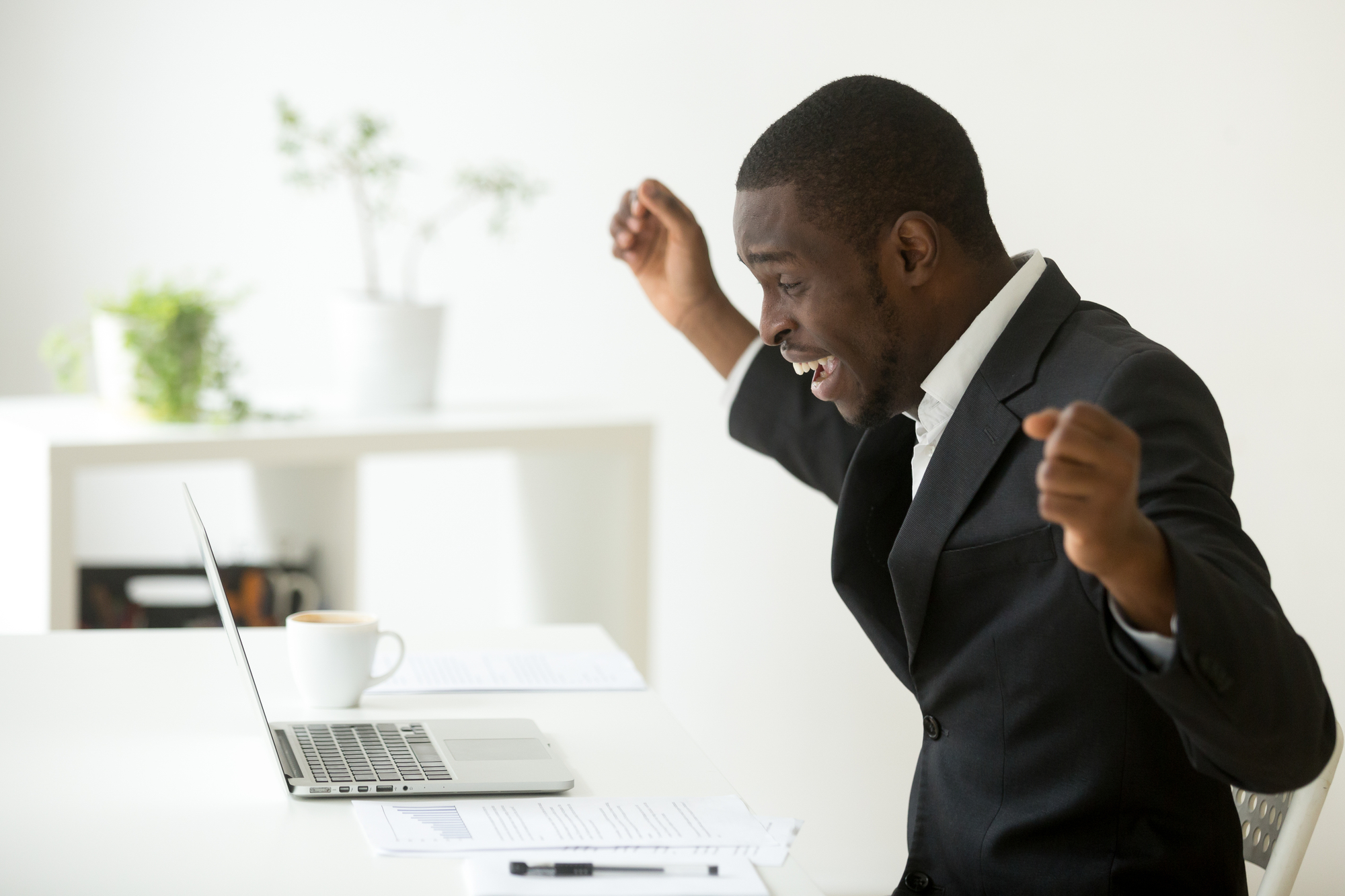 Happy african-american businessman celebrating success online